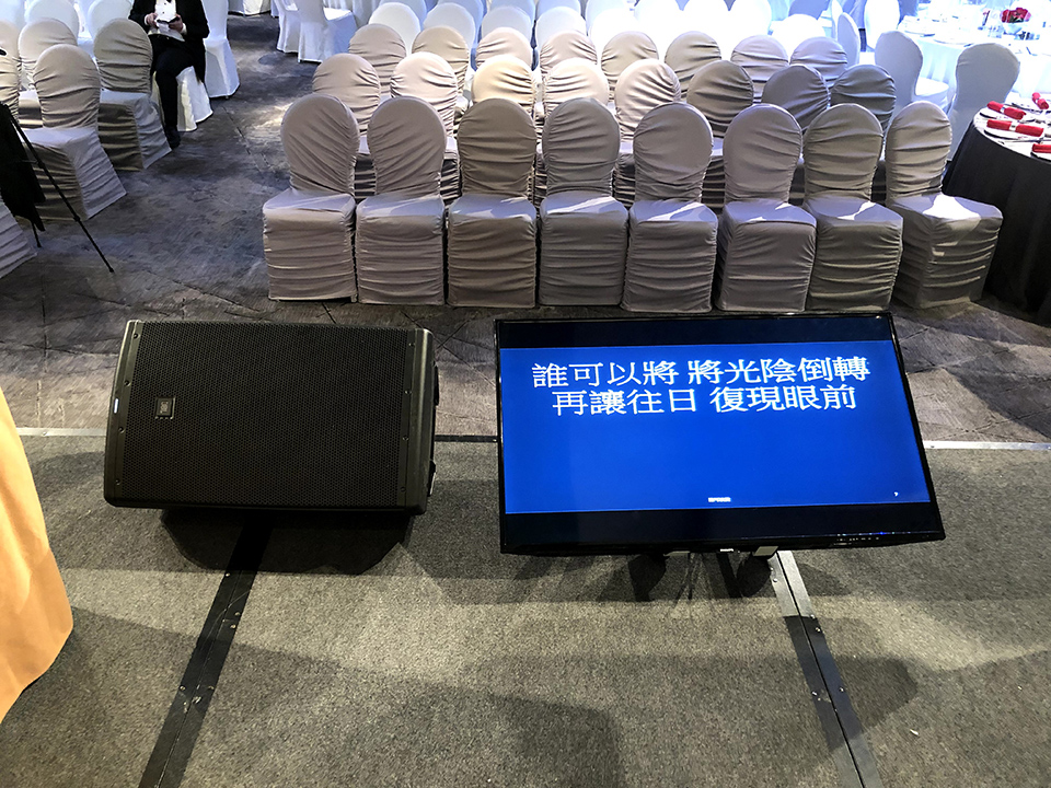 宴會場地內設有平面顯示屏幕與音響喇叭，座椅整齊排列